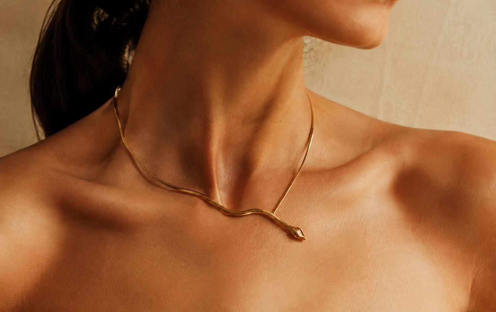 Gold serpent necklace worn on collarbone